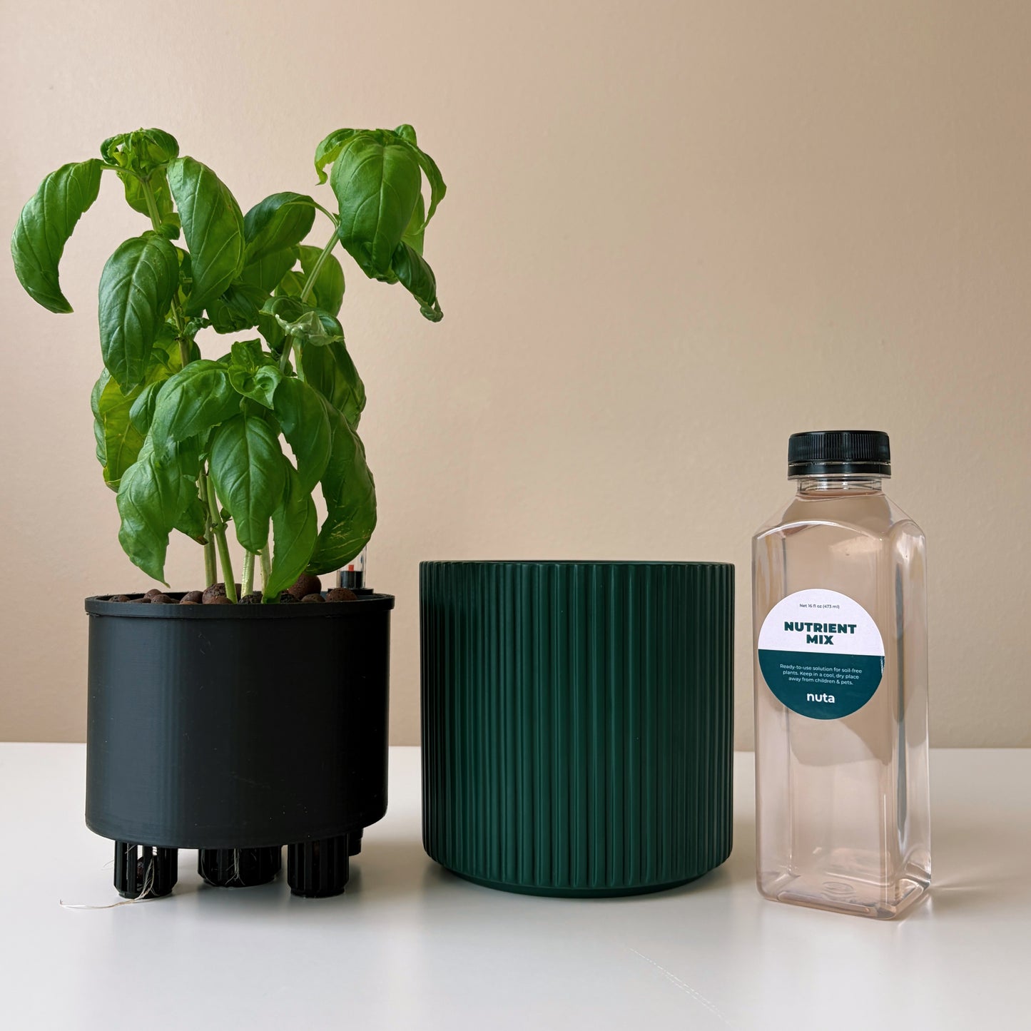 Potted plant, green container, and nutrient mix bottle on a white surface with a beige background